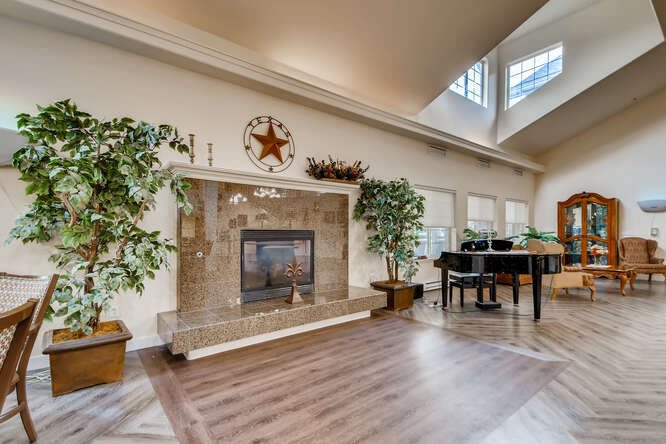 A spacious living room featuring a fireplace, grand piano, and abundant natural light.