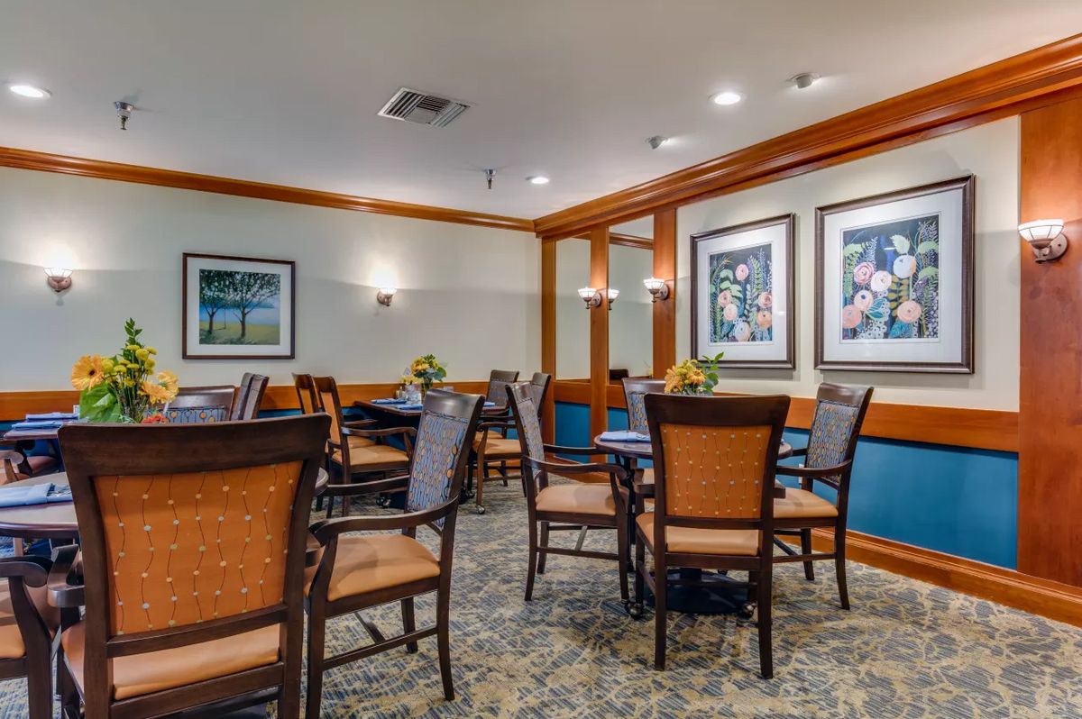 A cozy dining area with several tables and chairs, adorned with framed art on the walls.
