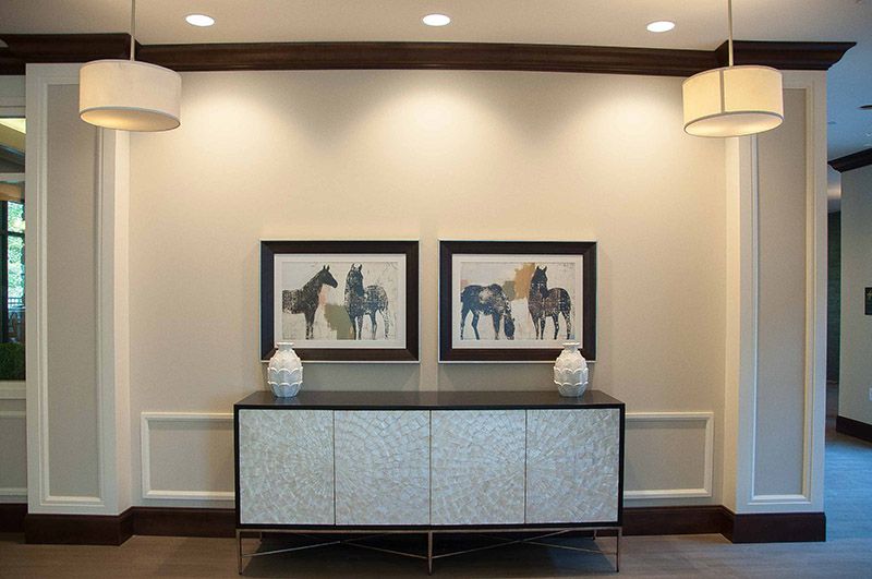 A modern interior featuring a console table adorned with two vases and framed artwork of horses on the wall.