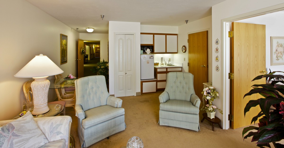 A cozy living area featuring two armchairs and a small kitchenette.