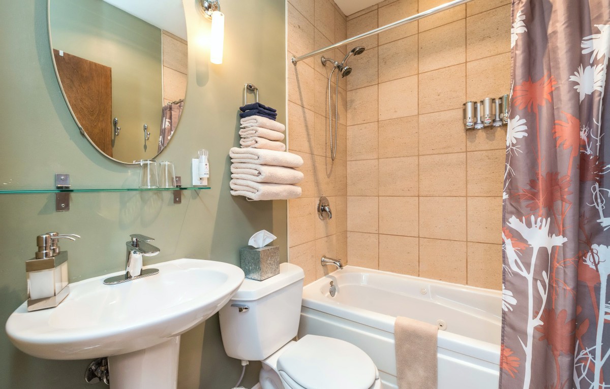 A clean and organized bathroom with a bathtub, sink, and neatly stacked towels.