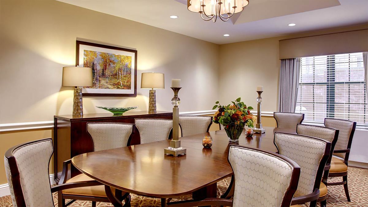 A well-decorated dining room featuring a wooden table, upholstered chairs, artwork on the wall, and a chandelier.