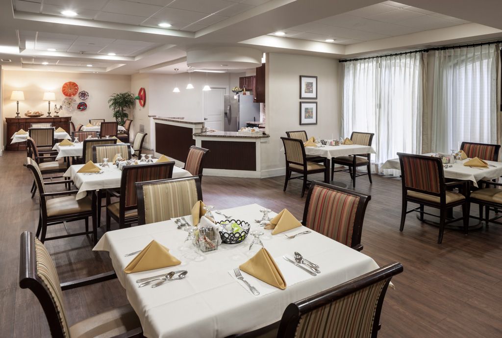 An elegantly set dining area with neatly arranged tables and chairs, featuring folded napkins on the tables.