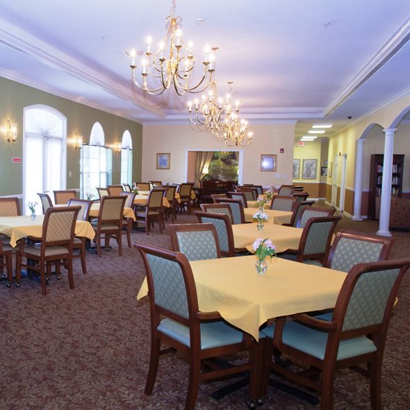 A spacious dining room with elegantly set tables and chandeliers.