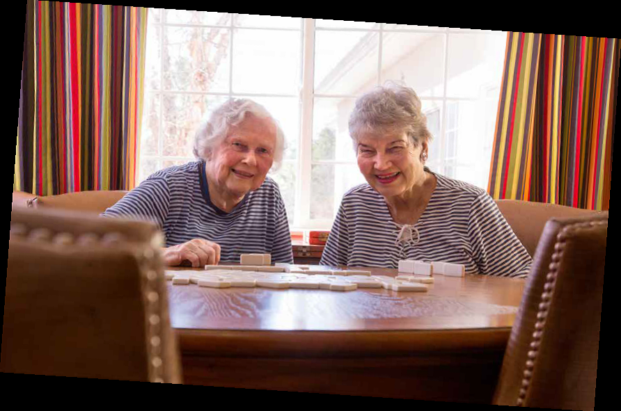Two seniors enjoying a game together at a table.