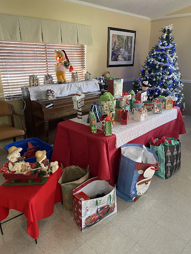 A cozy holiday setup featuring a decorated Christmas tree and a table full of festive decorations and gifts.