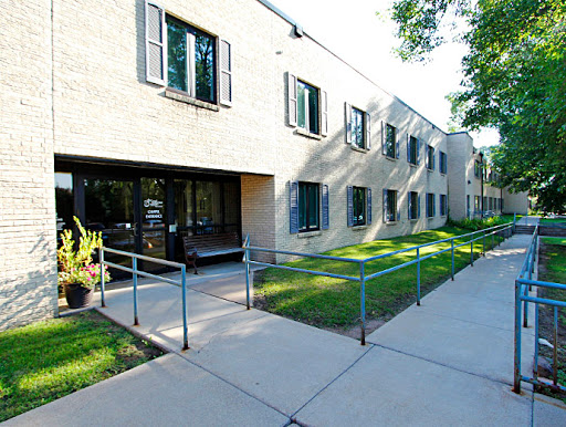 A modern building with a ramp leading to the entrance, surrounded by green grass and trees.