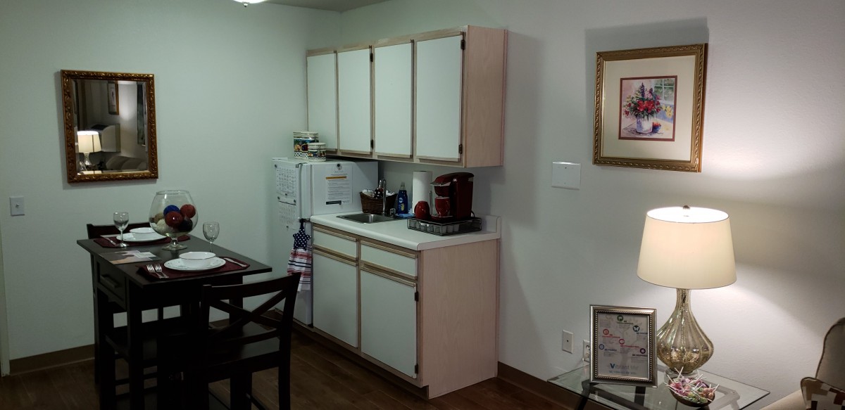 A cozy kitchen area with white cabinets and a countertop.
