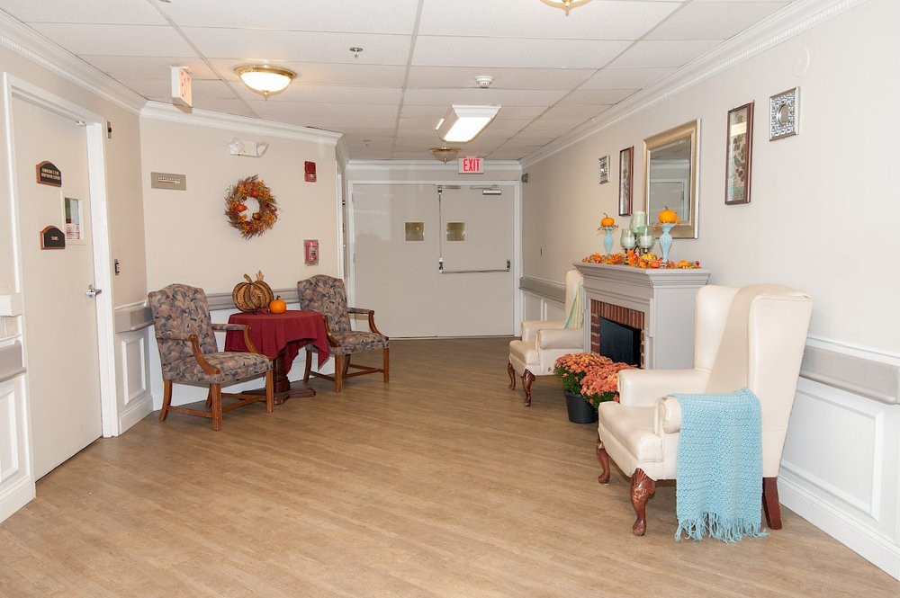 A cozy lobby area with chairs, a table, and a decorative fireplace.