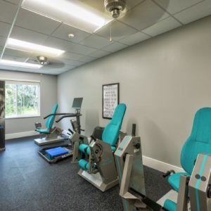 A compact gym room with exercise equipment and a large window.