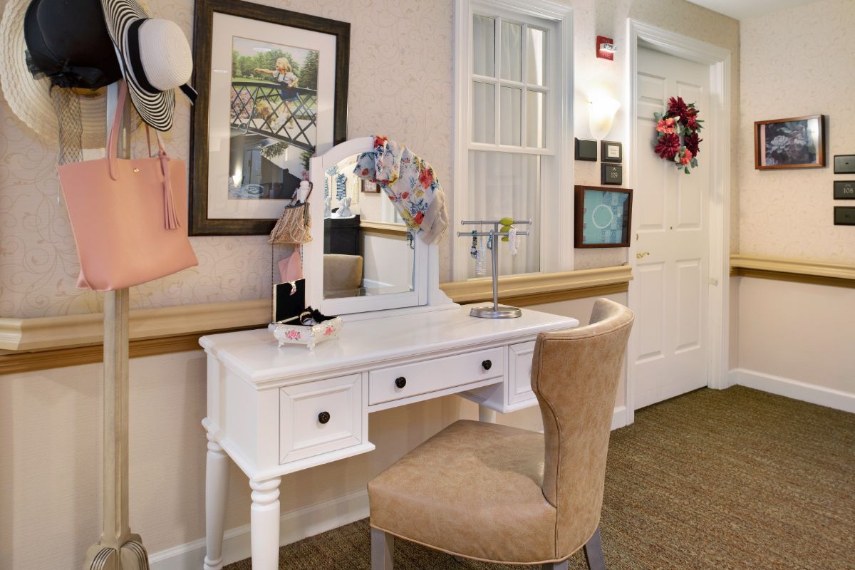 A stylish vanity setup with a mirror and flowers, complemented by a cozy chair in a warmly decorated room.