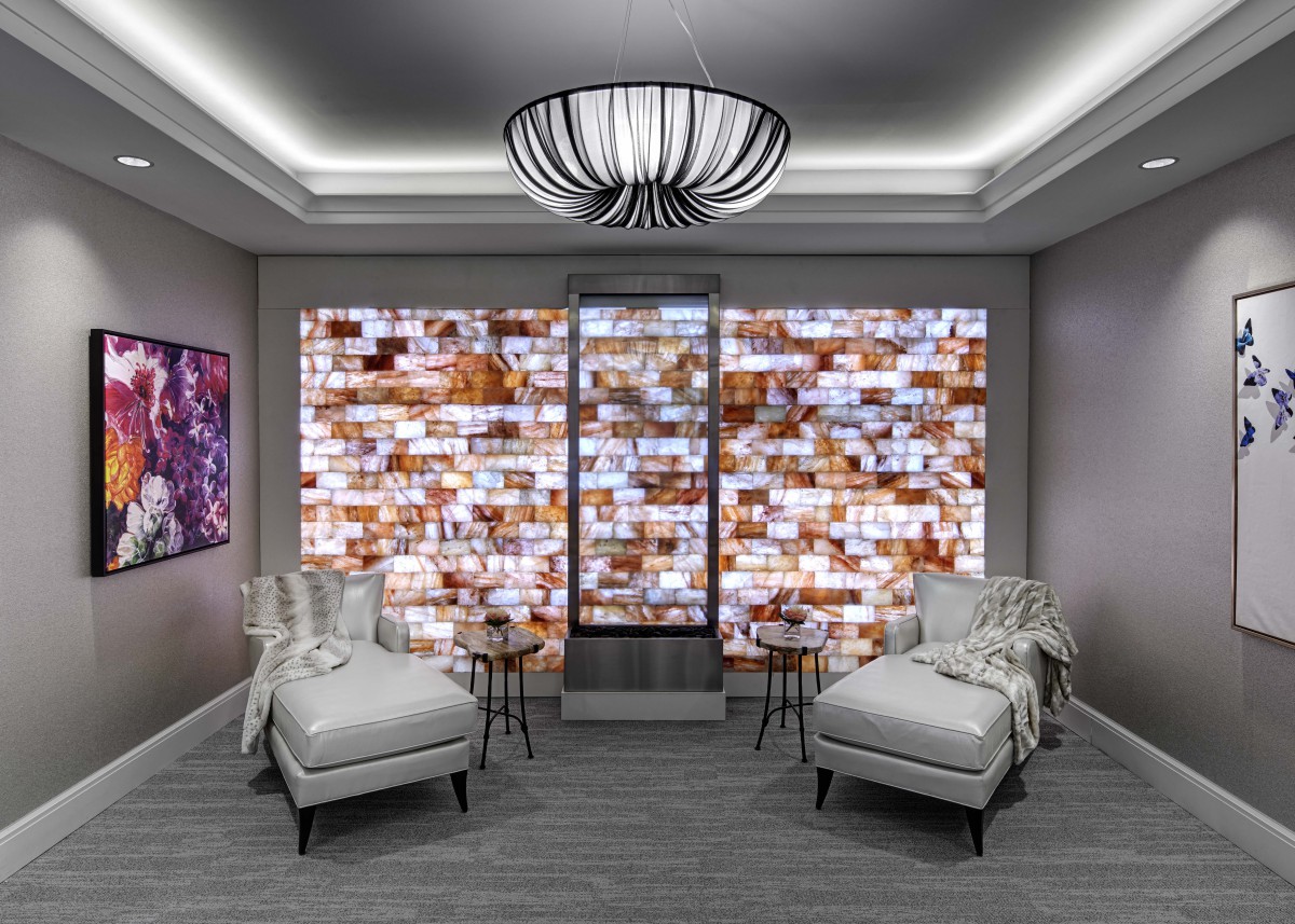A modern lounge area featuring comfortable chairs and a striking mosaic accent wall.