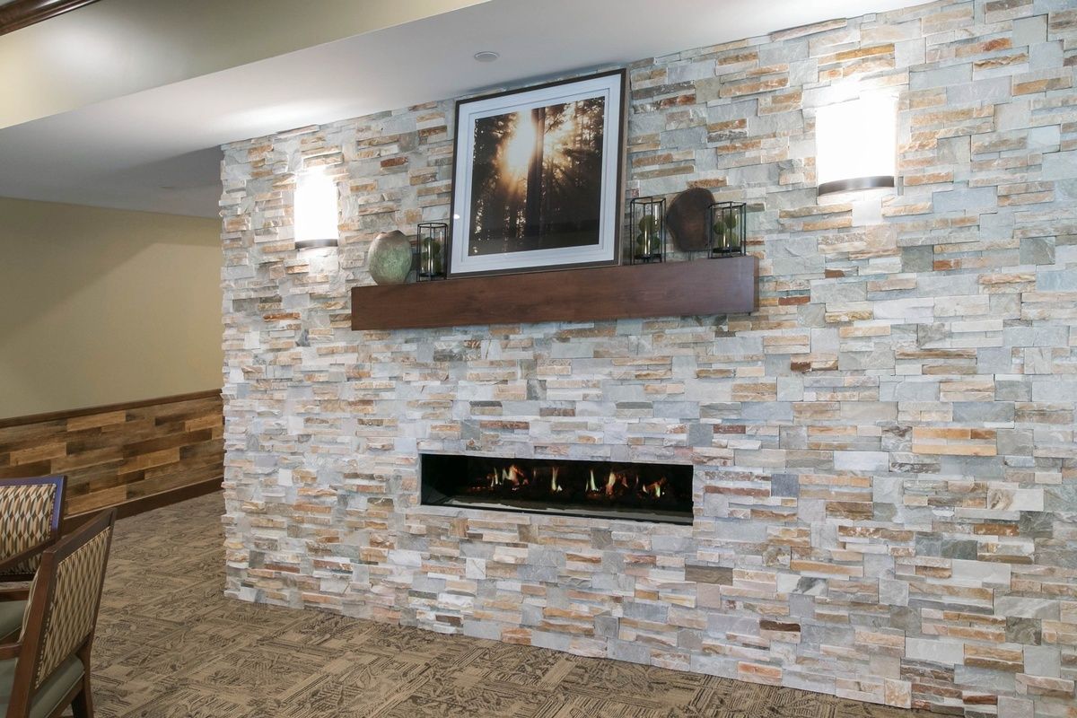A modern interior featuring a stone wall with a sleek fireplace and decorative mantelpiece.