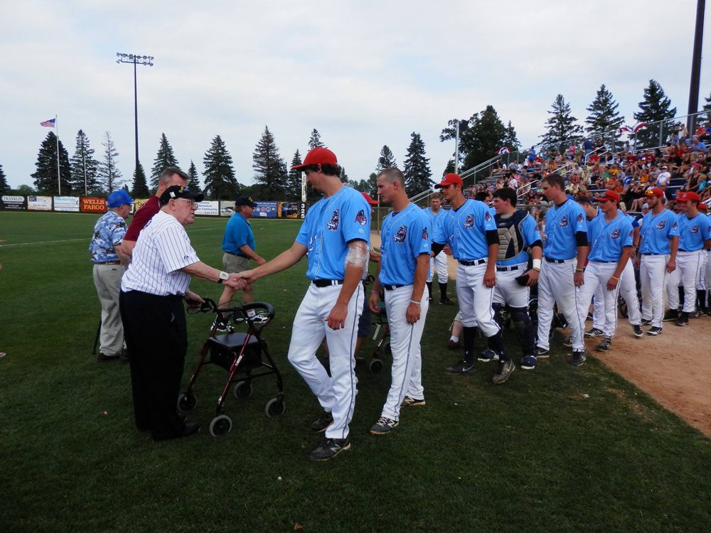A baseball team in blue uniforms shakes hands on the field.