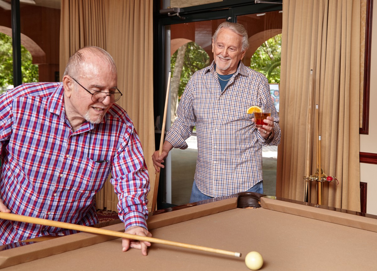 Two senior men enjoying a game of pool together.