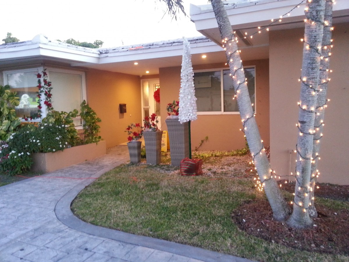 A welcoming house entrance with decorative lights and a garden pathway.
