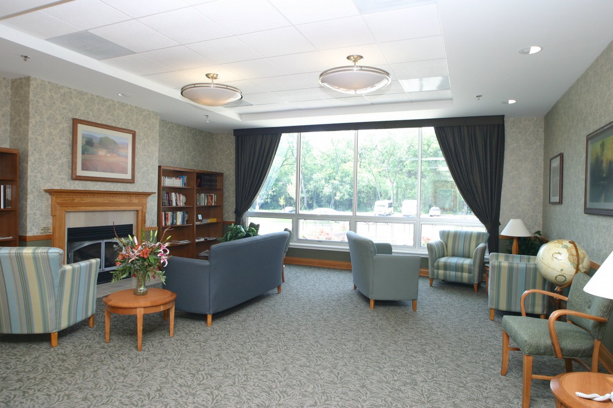 A cozy living room with comfortable seating, a bookshelf, and large windows letting in natural light.
