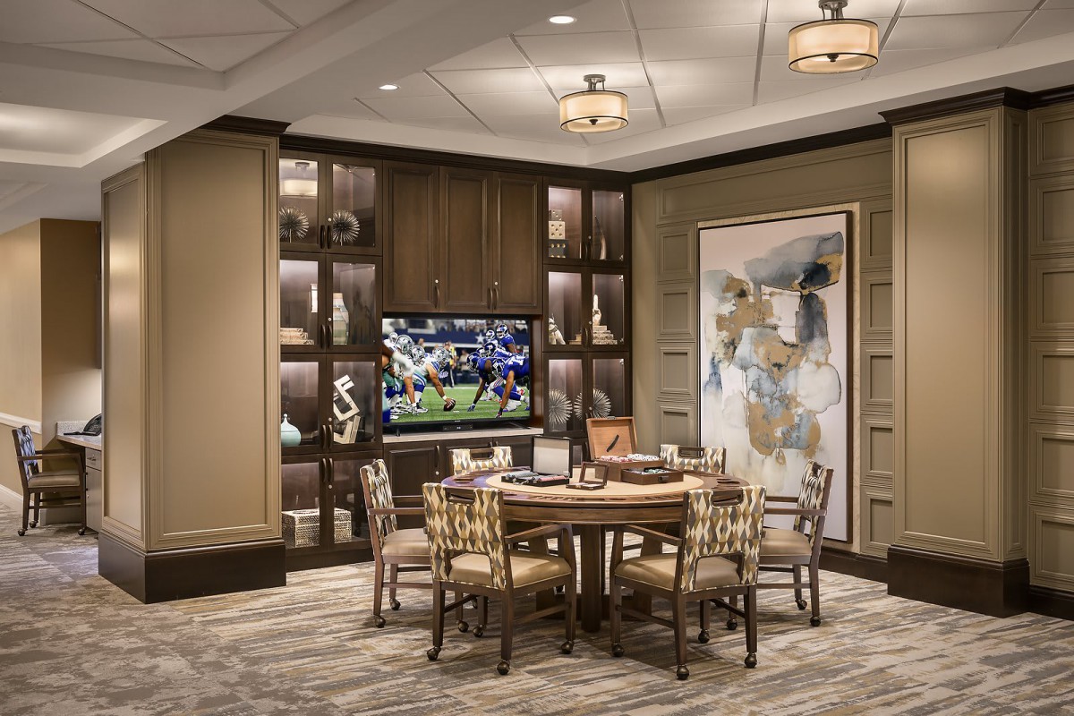 A luxurious room with a dining table, modern artwork, and a television displaying a sports game.