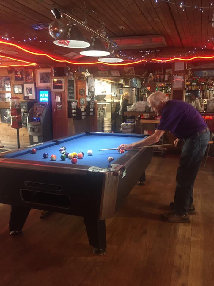 Person playing billiards in a cozy bar setting.