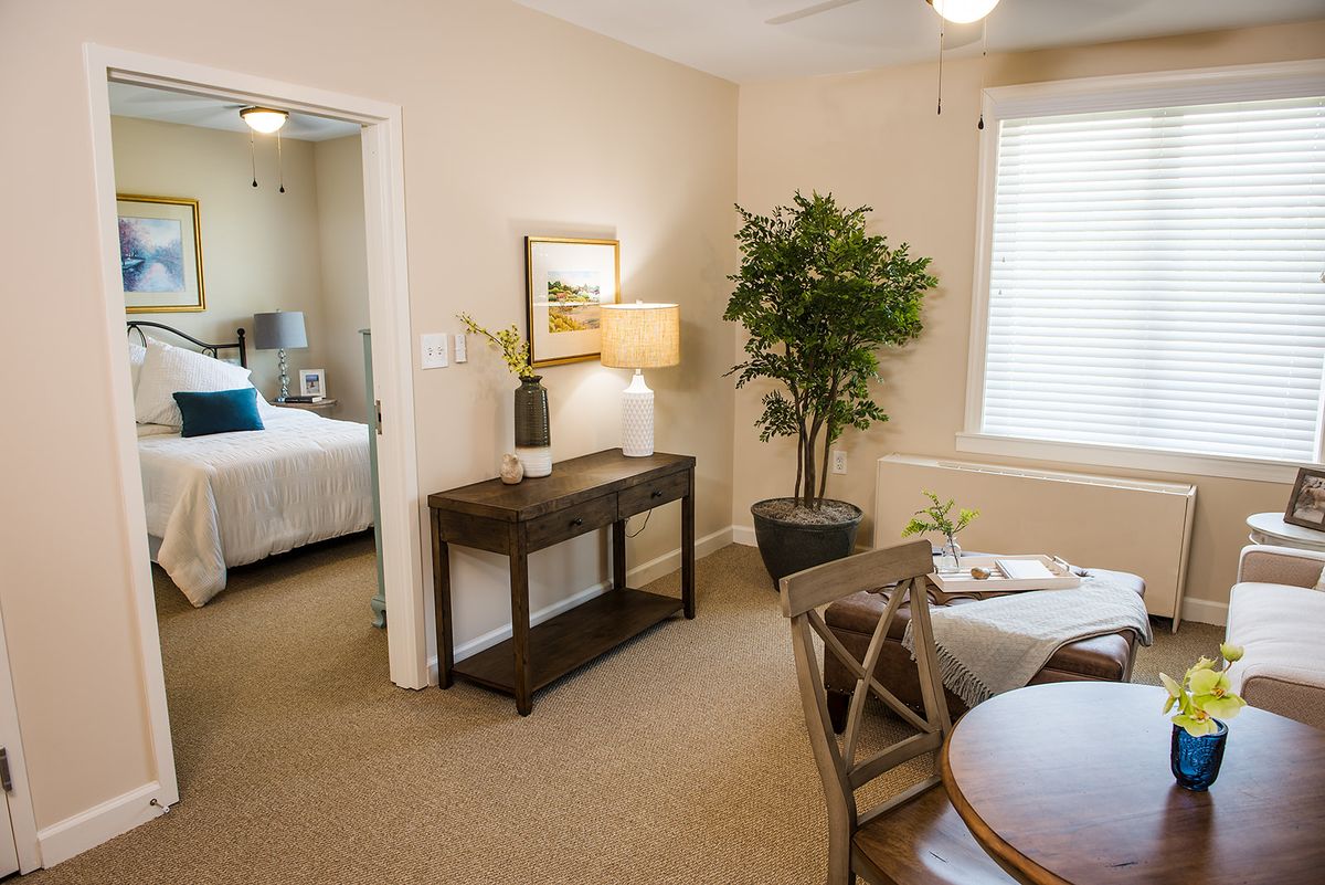 A cozy and well-decorated living area leading to a bedroom, featuring stylish furniture and decor elements.
