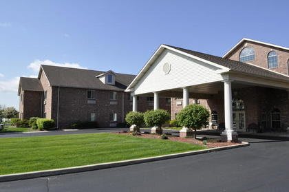 A hotel entrance with a landscaped lawn and columns.