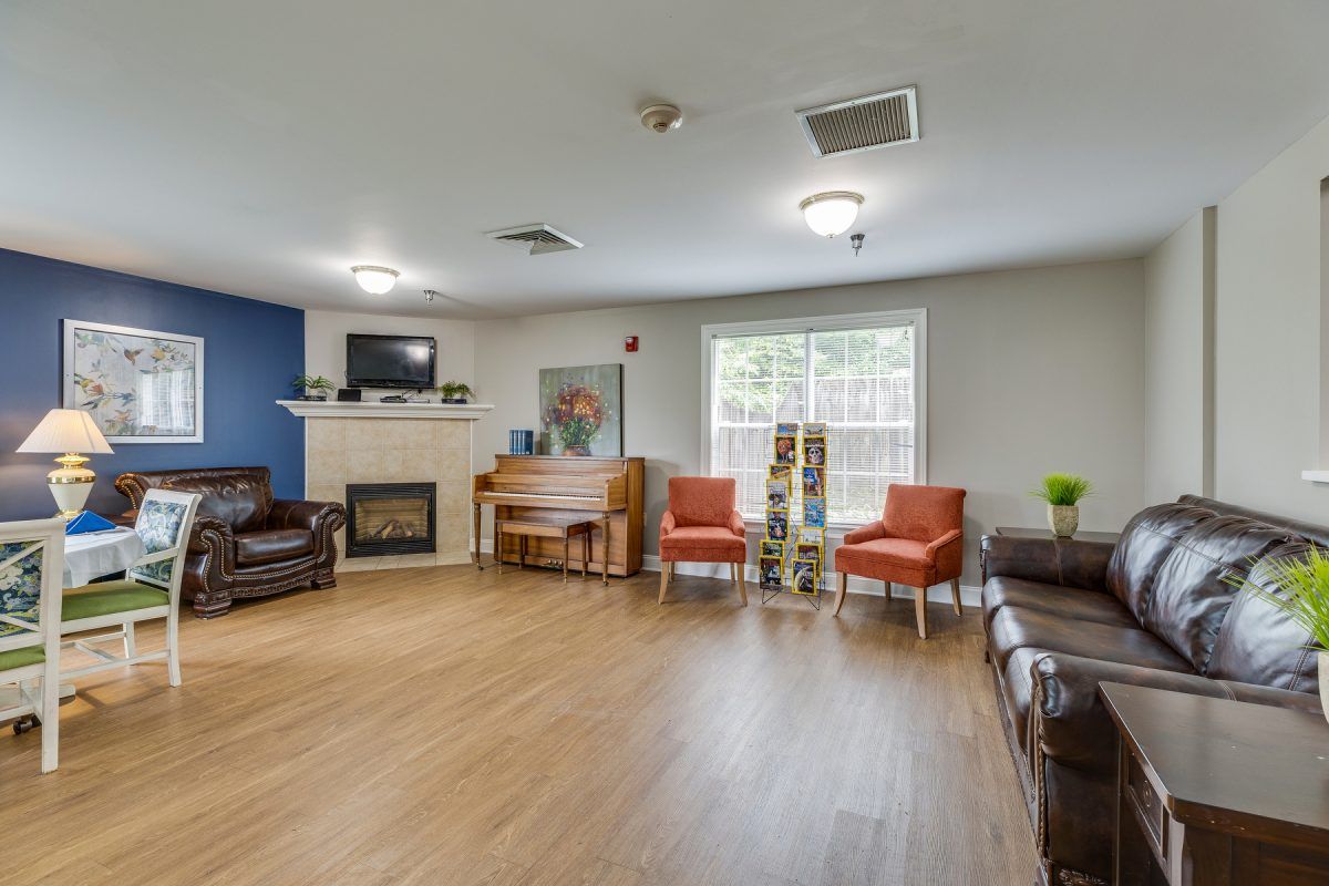 A cozy living room with a piano and fireplace, featuring comfortable seating and a television.