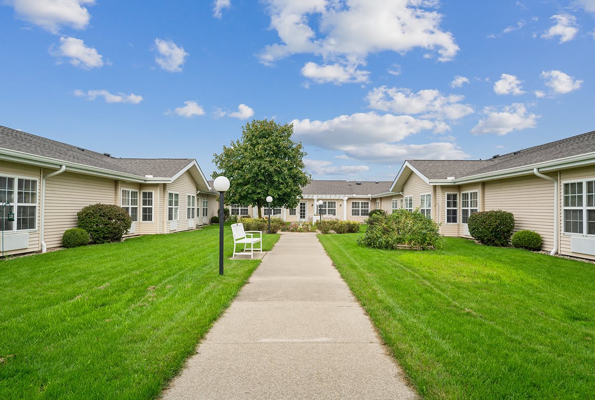 A well-maintained garden path leading to residential buildings under a clear blue sky.