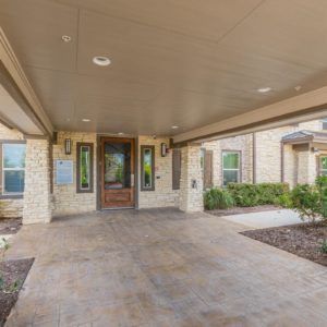 A covered entrance to a building with a paved driveway.