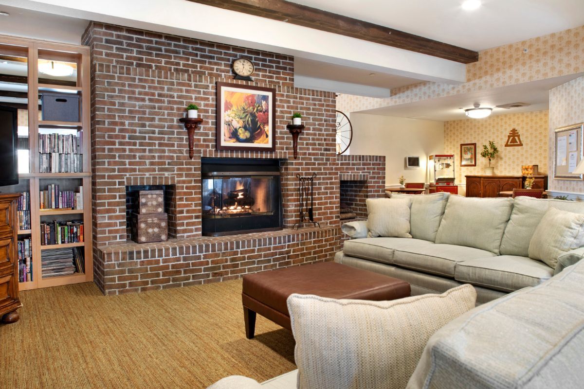 A cozy living room with a brick wall and a warm fireplace, featuring comfortable couches and a coffee table.