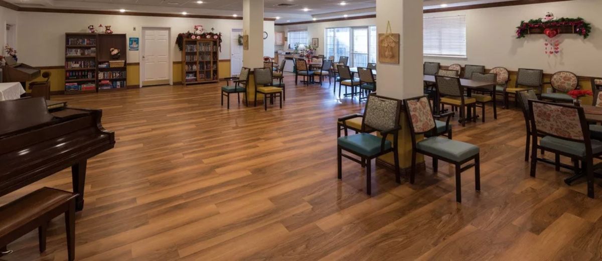 A spacious lounge area with wooden flooring and arranged chairs.