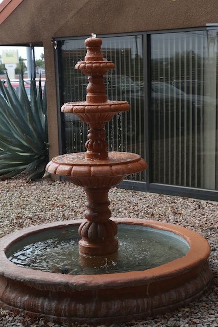 A decorative three-tiered terracotta fountain surrounded by gravel.