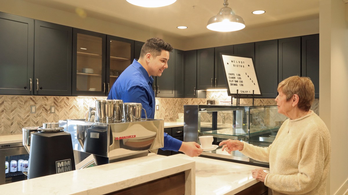 A barista serves a customer at a cozy coffee shop counter.