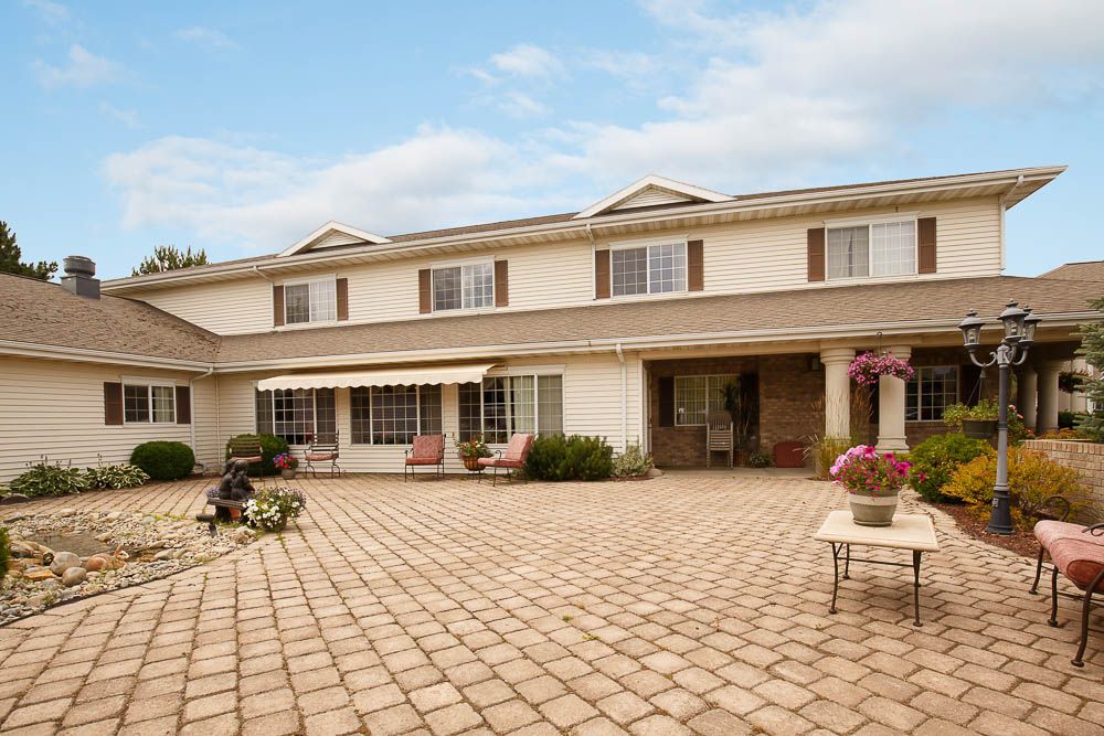 A spacious two-story residential house with a large patio area and outdoor seating.