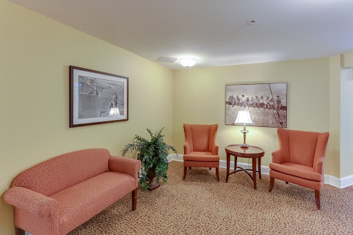 A cozy waiting area featuring orange seating, a small table, and decorative wall art.