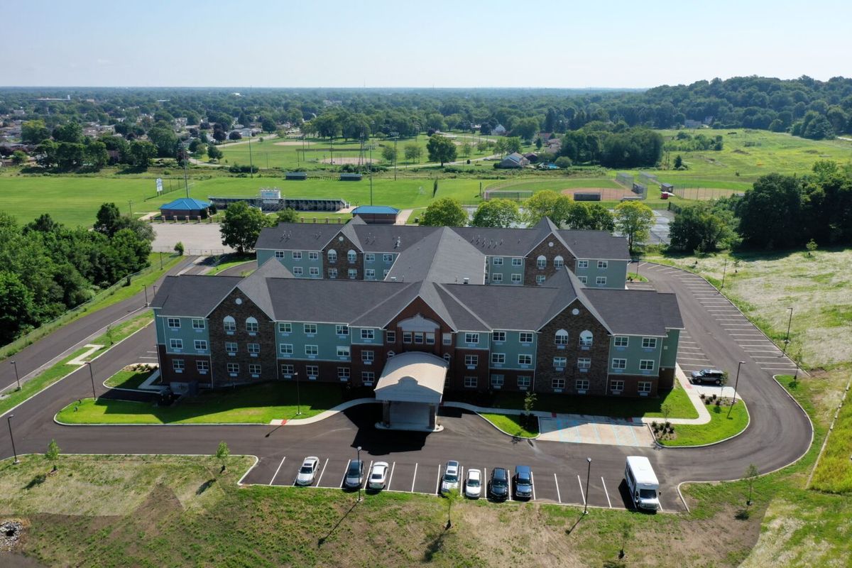 An aerial view of a large building with a parking lot in a landscaped area.