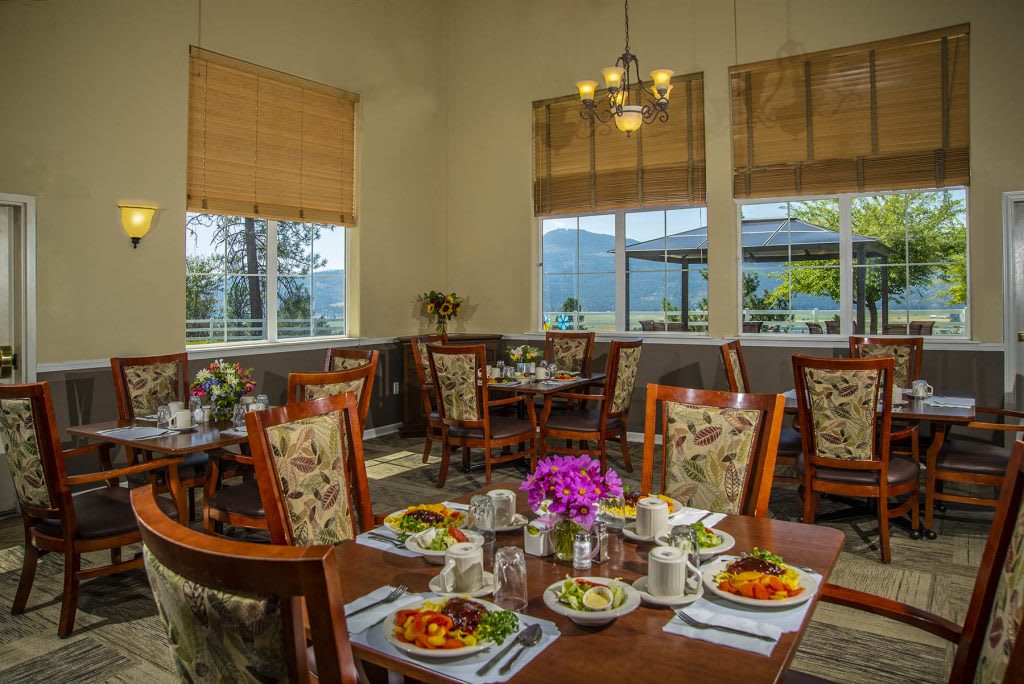 A cozy restaurant dining room with elegantly set tables and a view of the outside.