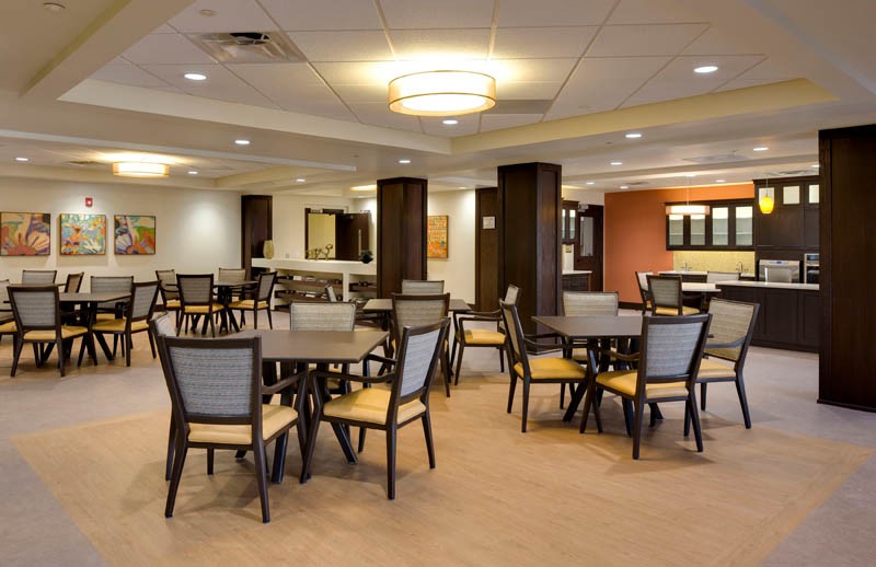 A modern dining area with neatly arranged tables and chairs, featuring warm lighting.