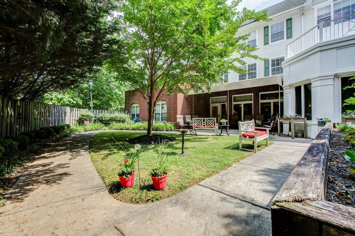 A peaceful garden area with seating and a path leading to a building.