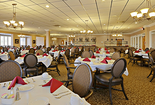 An elegant dining room set up for a meal, featuring neatly arranged tables with white tablecloths and red napkins.