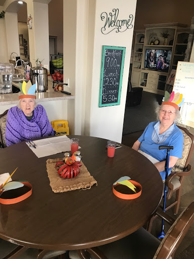 Two elderly individuals celebrating Thanksgiving with festive party hats at a decorated table.