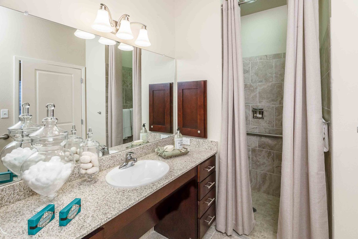 A modern bathroom with a sink, mirror, and shower area.