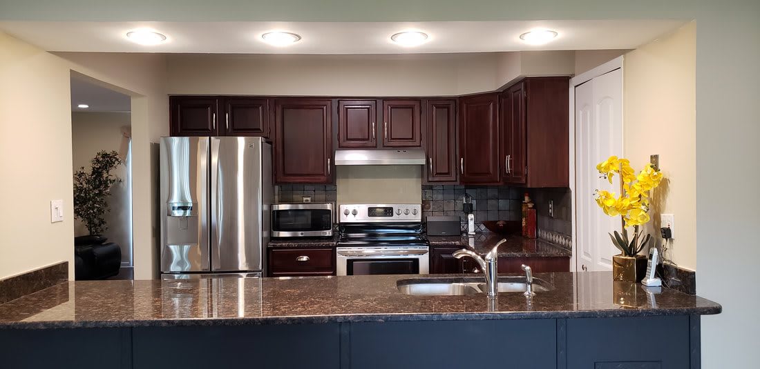 A modern kitchen with stainless steel appliances and dark wooden cabinets.