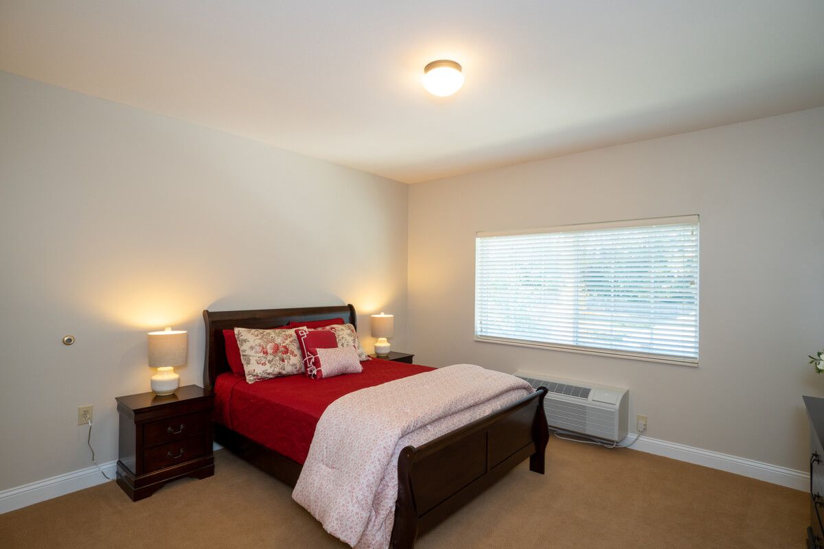 Bright and cozy bedroom with red bedding and matching nightstands.