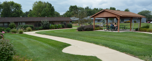 A serene park scene featuring a winding pathway and well-maintained grass, with buildings in the background.