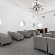 A modern conference room with minimalist seating and a central chandelier.