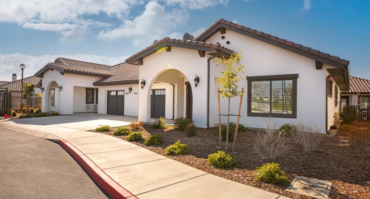 A modern residential house with a landscaped front yard and driveway, captured on a sunny day.