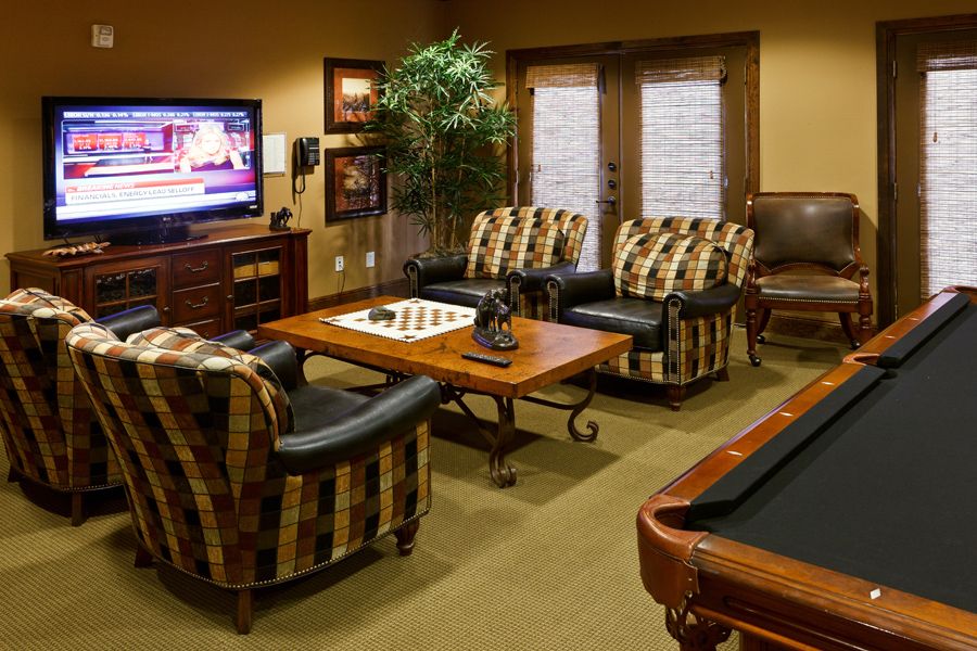 A cozy living room with a chess board, seating area, TV, and pool table.