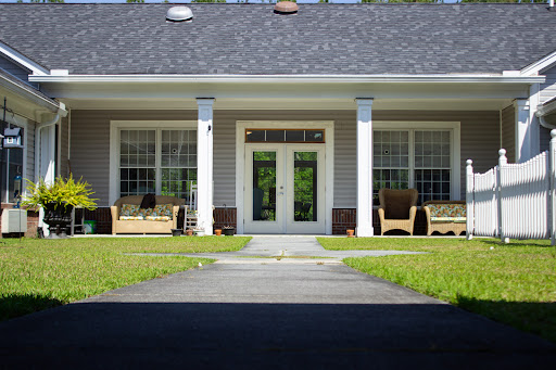 A welcoming entrance to a charming house with a well-maintained lawn and outdoor seating.
