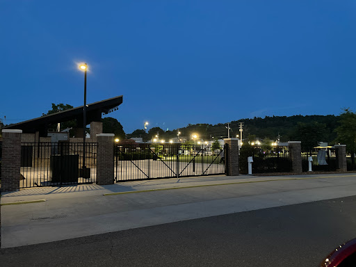 A view of a well-lit sports facility gate during dusk.