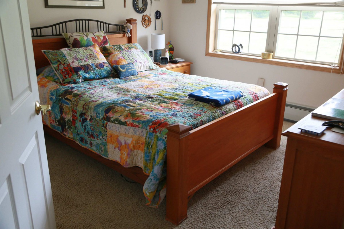 A cozy bedroom with colorful bedding and a wooden bed frame.